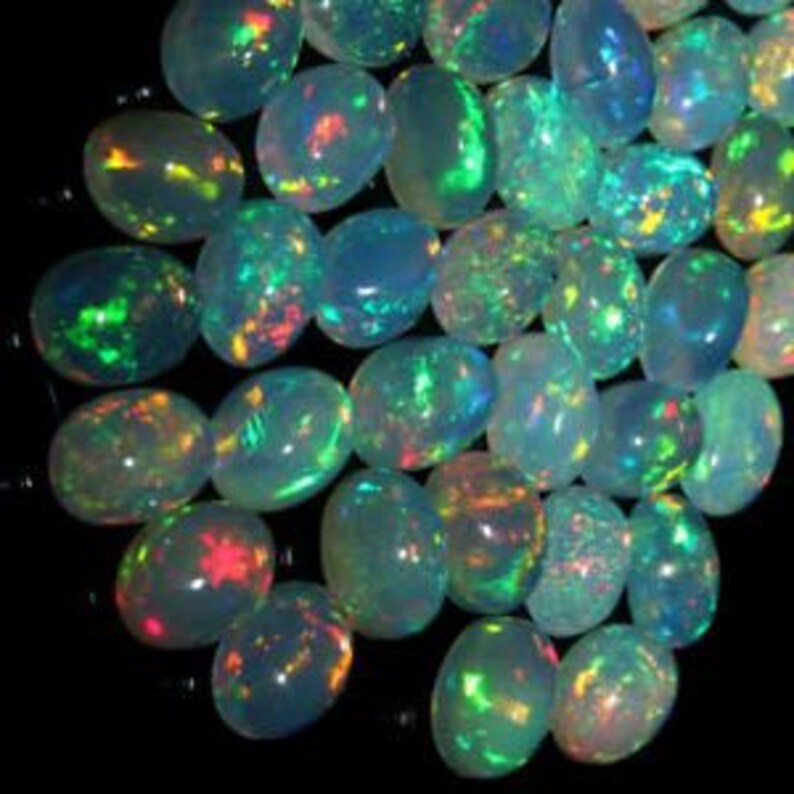 Puede incluir: Una colecci&oacute;n de piedras preciosas de &oacute;palo de forma ovalada e iridiscentes. Los &oacute;palos son una mezcla de blanco, verde y azul con destellos de color.