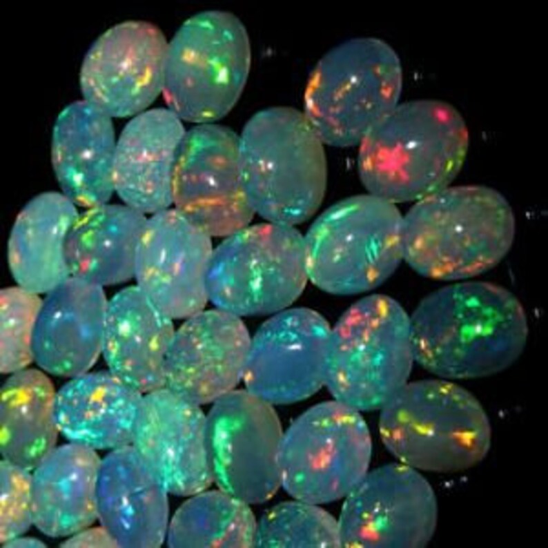 Puede incluir: Una colecci&oacute;n de piedras preciosas de &oacute;palo ovaladas e iridiscentes en varios tonos de verde, azul y blanco.