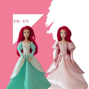 Può includere: Due bambole Ariel che indossano abiti da principessa diversi. La bambola a sinistra indossa un abito turchese con un corpetto bianco. La bambola a destra indossa un abito rosa. Entrambe le bambole hanno i capelli rossi e gli occhi blu. Il testo "FR/EN" è sullo sfondo.