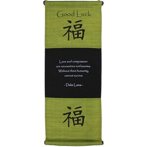 May include: A green fabric wall hanging with the Chinese character for "good fortune" written in black. The hanging also features the quote "Love and compassion are necessities not luxuries. Without them humanity cannot survive - Dalai Lama -" in white text.