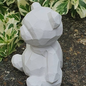 K&ouml;nnte beinhalten: Wei&szlig;e geometrische B&auml;renskulptur mit glatter, matter Oberfl&auml;che. Der B&auml;r sitzt mit dem R&uuml;cken zur Kamera und dem Kopf nach oben geneigt.