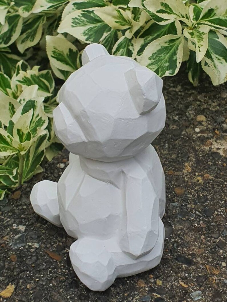 K&ouml;nnte beinhalten: Wei&szlig;e geometrische B&auml;renskulptur mit glatter, matter Oberfl&auml;che. Der B&auml;r sitzt mit dem R&uuml;cken zur Kamera und dem Kopf nach oben geneigt.