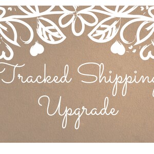 Könnte beinhalten: Ein braunes Papieretikett mit einem weißen floralen Rand und dem Text "Tracked Shipping Upgrade" in weißer Kursivschrift.