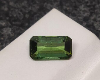 May include: A green gemstone with a rectangular emerald cut.