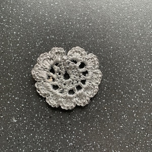 May include: A silver crocheted heart-shaped doily.