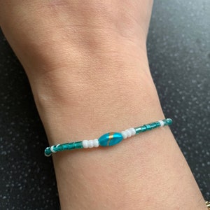 May include: A turquoise and white beaded bracelet with a single turquoise bead with a gold accent.