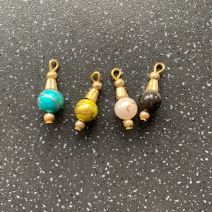 May include: Four decorative beads with gold accents. The beads are turquoise, yellow, white, and black.