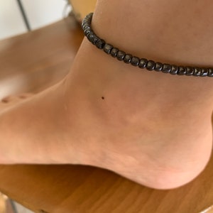 May include: A black beaded anklet on a person's ankle.