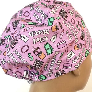 May include: A light purple surgical scrub cap with a repeating pattern of calculators, lipstick, money, and the words "Girl Math" and "It's basically free!". The cap also features sale tags and a credit card.