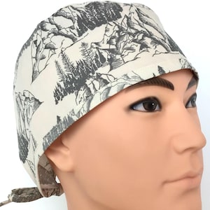 May include: A surgical scrub cap with a mountain and forest design in gray and white. The cap is tied in the back and is made of a soft, breathable fabric. The cap is designed to be worn during medical procedures.
