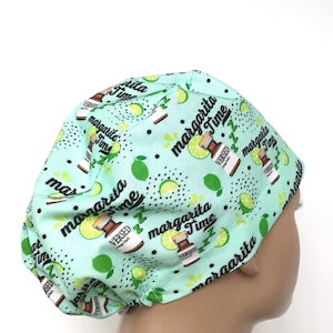 May include: A green scrub hat with a white and black print of limes and bottles with the text "Margarita Time" repeated throughout.