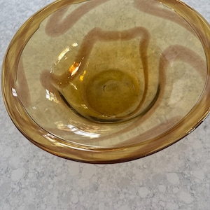 May include: A clear amber glass bowl with a wavy, brown design around the rim.