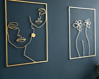 Set di decorazioni murali minimaliste con figure femminili in metallo dorato.