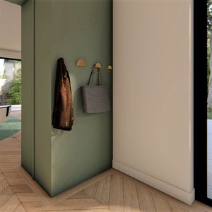 Peut inclure: Un mur vert avec une veste marron et un sac cabas gris accroch&eacute;s &agrave; des crochets dor&eacute;s. Le mur est dans un couloir avec un sol en bois.