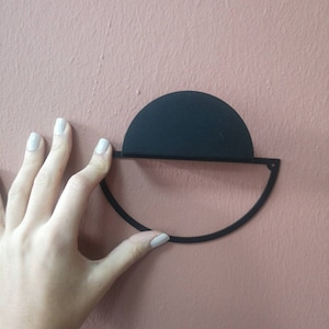Peut inclure: D&eacute;coration murale en m&eacute;tal noir en forme de demi-cercle avec un cercle plus petit sur le dessus. La d&eacute;coration est mont&eacute;e sur un mur rose.