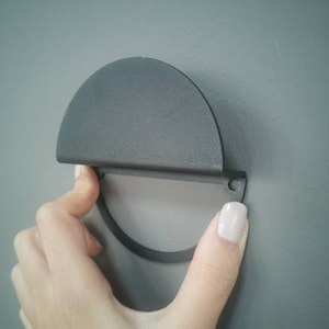 Peut inclure: Une poign&eacute;e de porte de placard en m&eacute;tal noir en demi-cercle avec une poign&eacute;e circulaire.