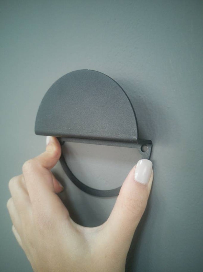 Peut inclure: Une poign&eacute;e de porte de placard en m&eacute;tal noir en demi-cercle avec une poign&eacute;e circulaire.