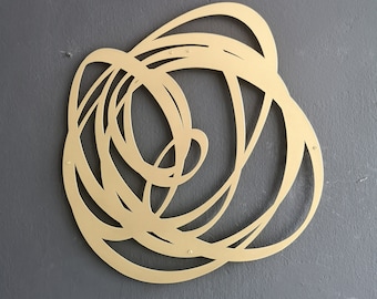 May include: A gold metal wall sculpture with a swirling, abstract design. The sculpture is made of thin metal and has a smooth, polished finish.