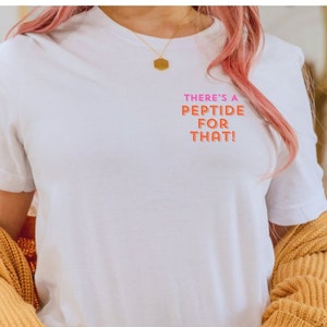 Puede incluir: Camiseta blanca con el texto "THERE'S A PEPTIDE FOR THAT!" en letras rosa y naranja.