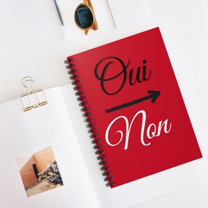 May include: Red spiral notebook with the words "Oui" and "Non" in black and white lettering. An arrow points from "Oui" to "Non".
