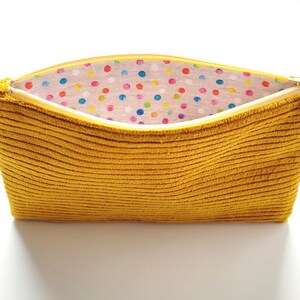 May include: A mustard yellow corduroy zippered pouch with a colorful polka dot lining.