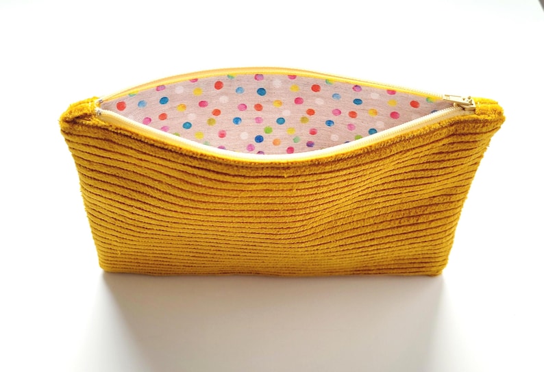 May include: A mustard yellow corduroy zippered pouch with a colorful polka dot lining.
