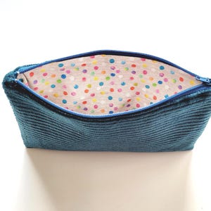 May include: A blue corduroy zippered pouch with a colorful polka dot lining.
