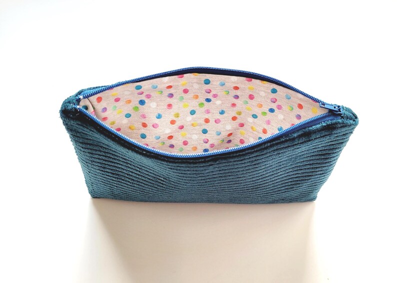May include: A blue corduroy zippered pouch with a colorful polka dot lining.