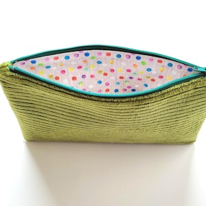 May include: A green corduroy zippered pouch with a colorful polka dot lining. The pouch is open and the zipper is visible.