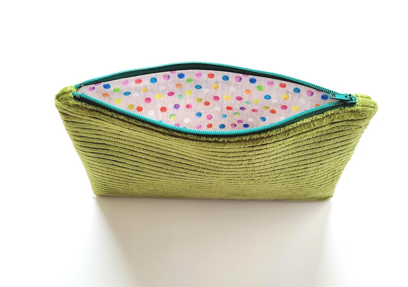 May include: A green corduroy zippered pouch with a colorful polka dot lining. The pouch is open and the zipper is visible.