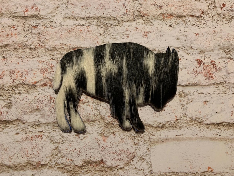 Puede incluir: Corte de bisonte de piel de vaca negra y blanca, un motivo occidental popular.