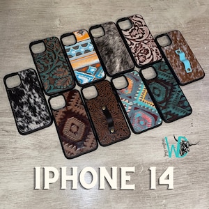 May include: Assortment of ten iPhone 14 phone cases with various designs. The cases feature a variety of patterns, including cowhide, paisley, and geometric designs. The cases are all black and have a cutout for the camera lens.
