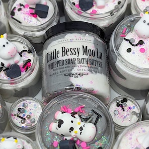May include: Multiple jars of whipped soap bath butter with a cow design on the lid. The jars are filled with a white and gray whipped soap and topped with black and pink sprinkles. The label on the front of the jar reads "Little Bessy Moo Lu Whipped Soap Bath Butter Bath Soap with Luxury Butters and Oils Mango Butter - Shea - Avocado".