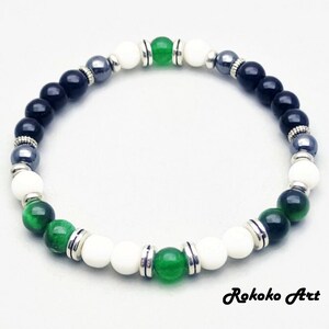 May include: A black, white, and green beaded bracelet with silver accents. The bracelet features black onyx, white howlite, green aventurine, and hematite beads.