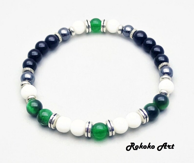 May include: A black, white, and green beaded bracelet with silver accents. The bracelet features black onyx, white howlite, green aventurine, and hematite beads.