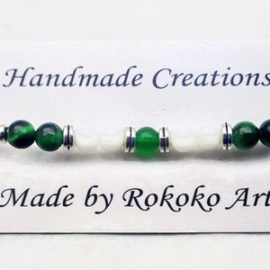 May include: A green and white beaded bracelet with silver accents. The bracelet is on a white card with the text "Handmade Creations" and "Made by Rokoko Art".