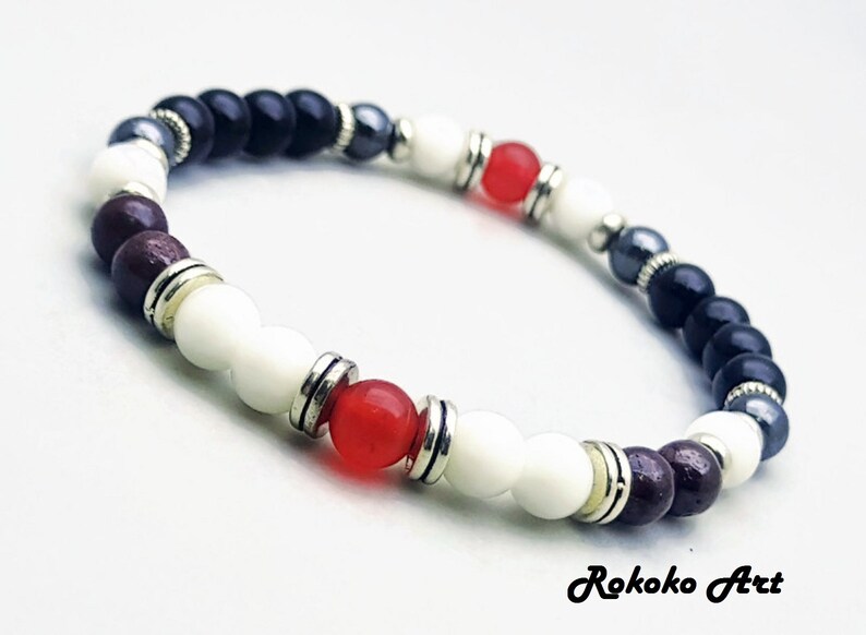 May include: A bracelet with black, white, red, and brown beads, separated by silver spacers. The bracelet has a silver clasp.