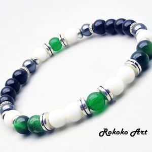 May include: A black, white, and green beaded bracelet with silver accents. The bracelet is made with round beads and has a simple design.