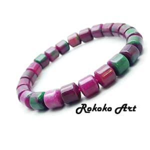 Puede incluir: Un brazalete de cuentas con piedras cuadradas en tonos rojos, rosas y verdes. Las cuentas están ensartadas para formar un círculo. El texto "Rokoko Art" es visible en la imagen.