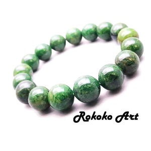 May include: A green beaded bracelet with a natural stone appearance. The bracelet features round beads in varying shades of green, strung together. The image includes the text "Rokoko Art".