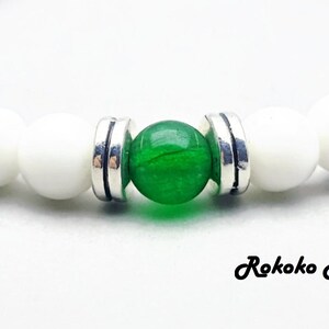 May include: A green jade bead bracelet with white beads and silver spacers. The bracelet is made with natural stones and is a beautiful piece of jewelry.