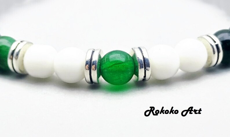 May include: A green jade bead bracelet with white beads and silver spacers. The bracelet is made with natural stones and is a beautiful piece of jewelry.