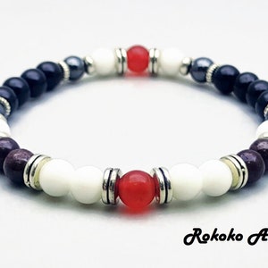 May include: A beaded bracelet with black, white, red, and brown beads. The bracelet has silver accents and is made with natural stones.