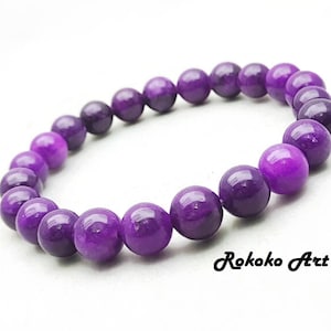May include: Purple gemstone bracelet with round beads. The beads are a gradient of purple shades.