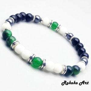 May include: A bracelet with black, white, and green beads, separated by silver spacers. The bracelet is made of natural stones and is a stylish accessory.