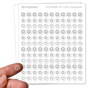 Op de afbeelding: Vel met 132 transparante stickers, elk 7,5 mm in diameter, met smiley gezichten, sterren en harten. De stickers zijn wit met zwarte contouren. Een vinger houdt een stersticker vast.