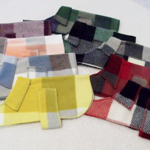 May include: Assortment of plaid dog coats in various colors, including red, yellow, blue, pink, and gray. The coats have a collar and are made of a soft, comfortable fabric.