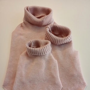 May include: Three pink turtleneck sweaters of different sizes, all with ribbed collars.