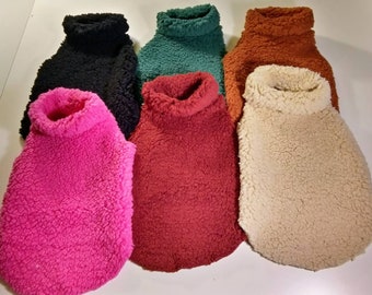 May include: Six turtleneck sweaters in different colors: pink, red, beige, teal, black, and brown. The sweaters are made of a soft, fluffy material.