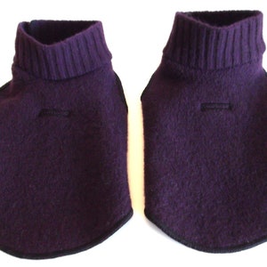 May include: Two purple turtleneck sweater collars with black trim. The collars are made of a soft, fuzzy material.